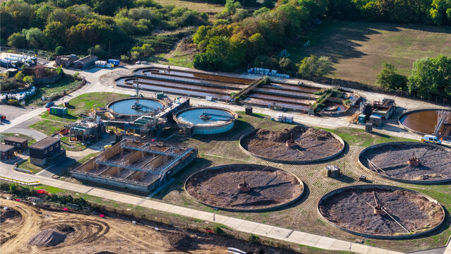 Farnham, England, United Kingdom - 15 September 2026: Aerial view of the Waste Water Treatment Works featuring circular sedimentation tanks and aeration basins surrounded by green fields.