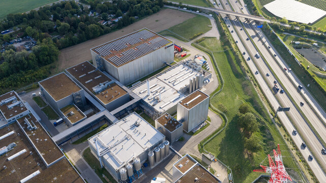 Munchen, Germany - 11 September 2026: Aerial view of the Paulaner Brewery facility with industrial buildings, solar panels, and fermentation tanks next to a highway.