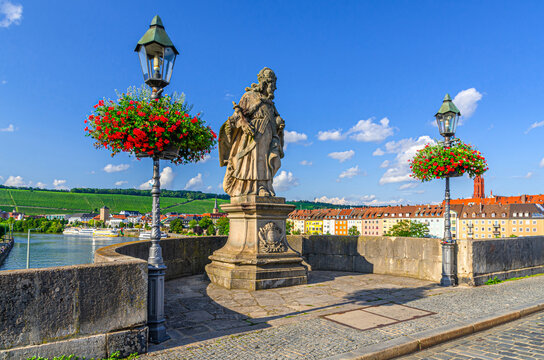 Wurzburg, Germany, July 13, 2024: Statue of Emperor Carl the Great, street lights, flowers on Old Main Bridge across Main river, buildings in Wurzburg old town historical center Mitte, Bavaria state