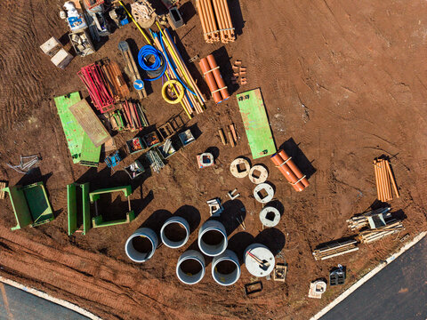 Stafford, England, United Kingdom - 13 September 2026: Aerial view of Hopton and Coton construction site with concrete pipes, orange drainage tubes, and green formwork panels on brown earth.