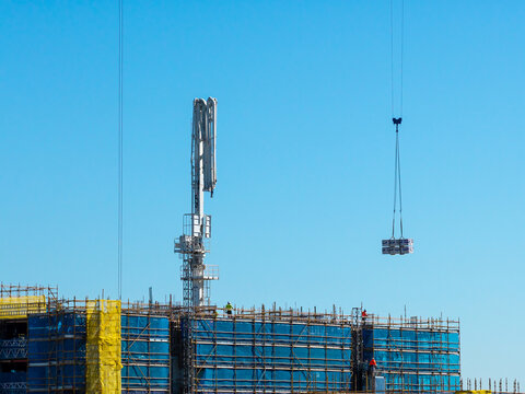 Castle Hill, Australia - 15 September 2026: Aerial view of Deicorp Showground Pavilions construction site with scaffolding, blue netting, concrete pump, and crane lifting load.