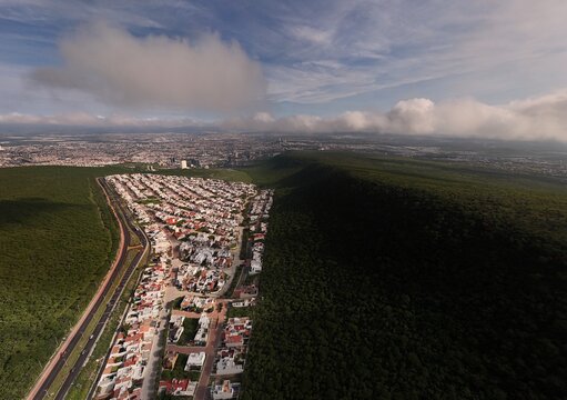 Santiago de Queretaro, Mexico - 14 September 2026: Aerial view of Parque Nacional El Cimatario bordering a residential area with city skyline in the distance under a cloudy sky.