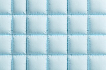 Obraz premium Light blue quilted square tiles background texture. Soft padded fabric pattern with stitched edges creates geometric surface. Minimalist interior decor element for wall upholstery design. Modern