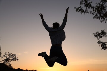 Fototapeta premium Peace and harmony. Silhouette of man jumping on sunset outdoors