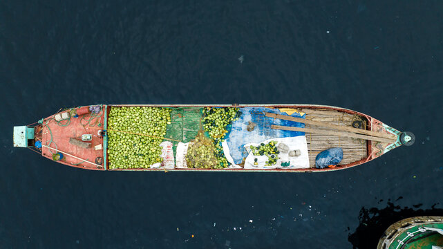 Dhaka, Bangladesh - 17 March 2023: Aerial view of a cargo boat at Sadarghat loaded with a large quantity of green watermelons, floating on the dark waters of the Buriganga River.