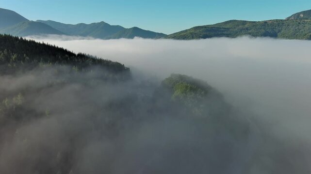 Aerial foggy mountain landscape with road. Morning mist covering forest and hills, 4k