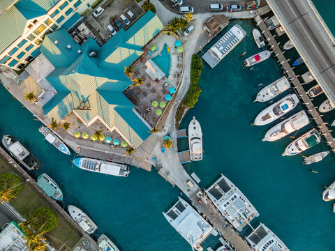 New Providence, The Bahamas - 03 January 2026: Aerial view of Paradise Island marina with a green-roofed building, yachts and catamarans docked in turquoise water, and a bridge.