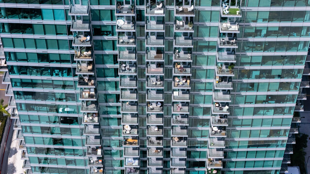 Los Angeles, California, United States - 13 September 2026: Aerial view of the modern glass facade of a high-rise building in the Miracle Mile district, featuring rows of balconies.