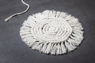 White macrame decorative item with fringe details, finished handicraft.