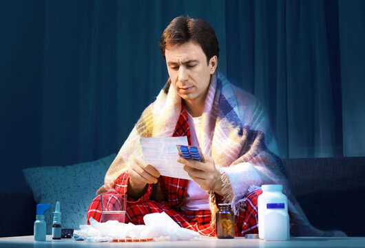 Sick man with cold and flu symptoms reading a prescription for medicine and treatment during an illness, infection, and recovery, practicing self care.