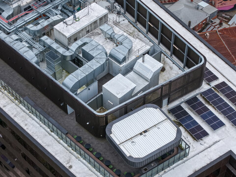 Ringwood, Australia - 13 September 2026: Aerial view of rooftop HVAC systems, solar panels, and a small outdoor seating area on a modern building.