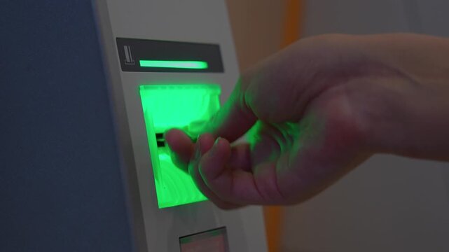 Close-up of hands of woman inserting credit card into ATM opening her bank account to conduct financial transaction and withdraw money from ATM
