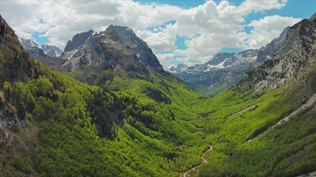 Aerial view of amazing rocky mountains in snow and green valley, Prokletie park, Montenegro and Albania, 4k