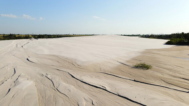 Spreading industrial waste forming a white artificial desert landscape under bright blue sky, revealing environmental impact