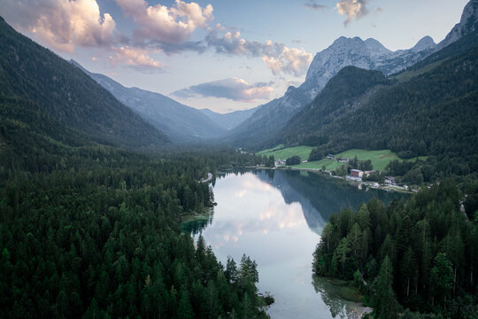 Ramsau bei Berchtesgaden, Germany - 24 August 2024: Aerial view of Hintersee surrounded by dense pine forests, alpine mountains, and calm lake waters under a soft evening sky.