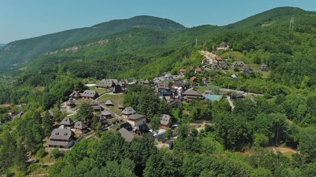 Aerial view of Drvengrad Kustendorf ethno village on Mokra Gora, Serbia, surrounded by green hills and mountains, 4k