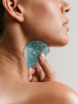 Woman pressing blue gel cold pack against jaw and neck for dental trauma relief with visible skin texture and clean background copy space