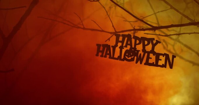 Happy Halloween text hanging in mysterious wilderness covered in dense smoke and fog. Dramatic smoky orange atmosphere effect around bare branches in deserted woodland for spooky Halloween background.
