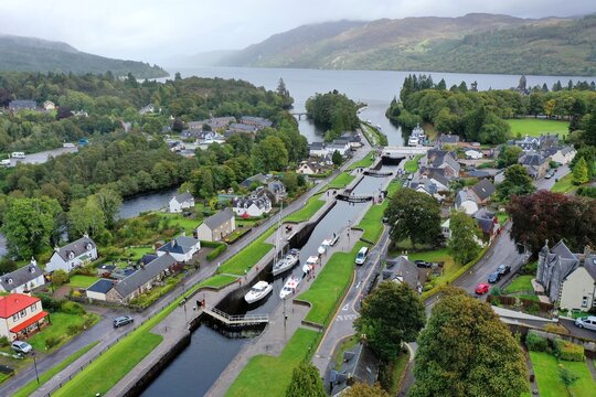 Aerial view of Fort Augustus Locks with boats navigating the canal, surrounded by historic buildings and lush greenery in Fort Augustus, Scotland, United Kingdom.