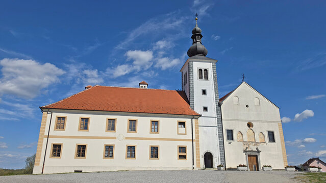 Historic white monastery complex with a red tile roof and tall domed bell tower against a blue sky