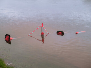 Red floating buoys mark water hazard zone. Red and white striped barrier warns of danger. Water surface reflects safety equipment. Ideal for safety, construction, or environmental projects © mark_gusev