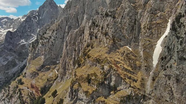 Aerial view of amazing rocky mountains in snow and green valley, Prokletie park, Montenegro and Albania, panorama 4k