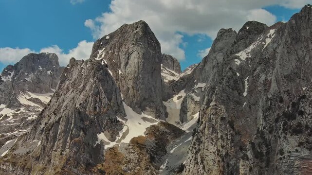 Aerial view of amazing rocky mountains in snow and green valley, Prokletie park, Montenegro and Albania, panorama 4k