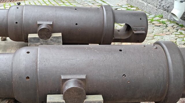 A pair of old cannons sitting on a stone ground