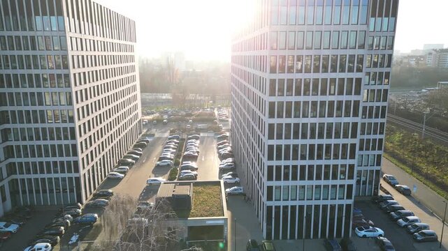 Aerial view of modern office buildings with sun flares illuminating the scene, showcasing architectural design and urban environment. Business district and contemporary city landscape at sunset time