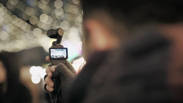 Man Records Christmas Market Lights with Gimbal Camera at Night in Warsaw