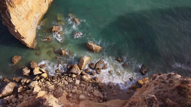 Aerial view of ocean waves crashing on rocky cliffs in portugal