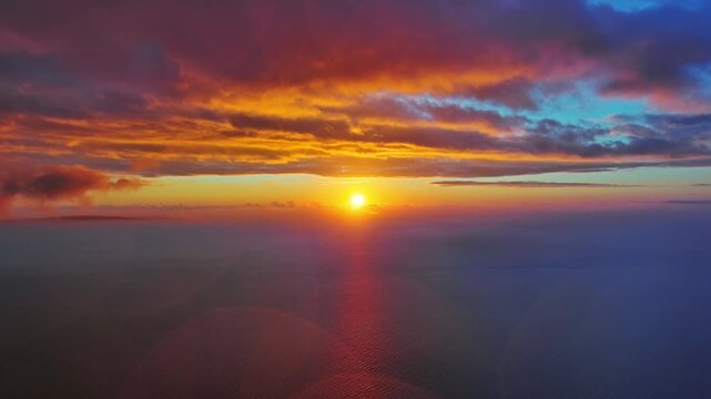 Aerial view of bright sun setting over calm sea. Scenic view of ocean horizon with dramatic clouds. Natural landscape background, 4k