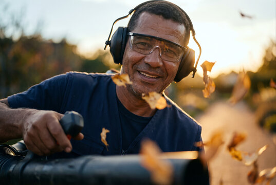 Smiling gardener using a handheld leaf blower