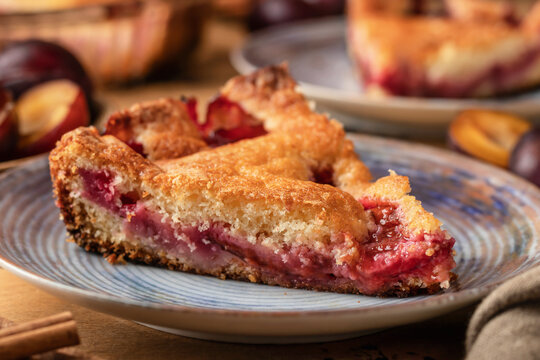 Homemade New York Times plum cake. Slice of autumn fruit pie in a plate on wooden background close up. Home cooking, recipe
