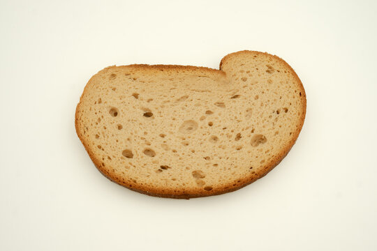 Slice of golden toasted bread on light cream background view closeup, showing porous crumb and browned crust texture filling frame