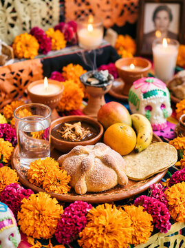 Table ofrenda features sweet bread fruit water glass and orange flowers for Day of the Dead ancestors remembrance altar. Mexican carnival Dia de los Muertos or Day of the Dead Catrina with copy space.
