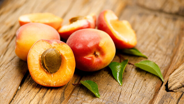 Apricots, close-up of fresh organic apricots fruits on a rustic wooden table. Fresh bio apricot with leaves closeup, top view 