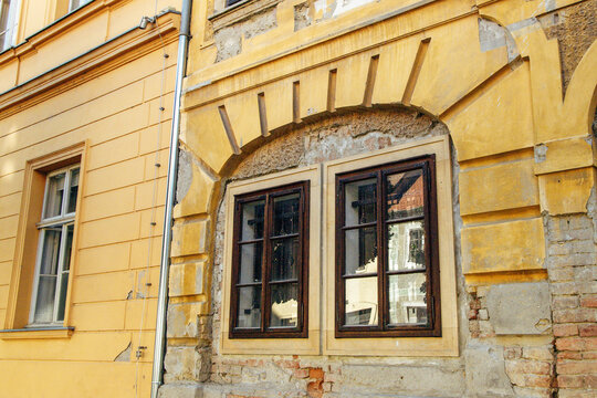 Historic building facade featuring ornate window designs in a vibrant yellow hue