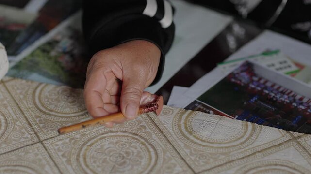 View of artisan using a wooden tool to craft intricate patterns on fabric in Guizhou, China.