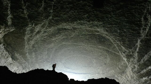 View of a person walking across the rocky terrain inside the vast cavernous Musk Cave in Anshun, Guizhou, China.