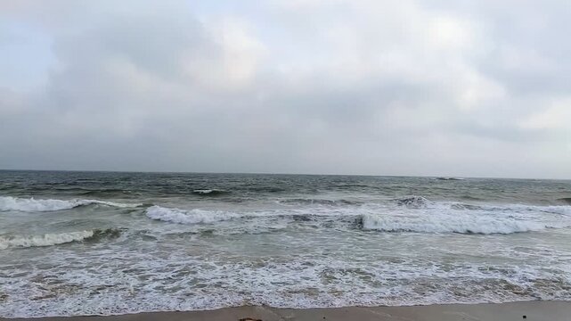 Ocean waves rolling onto a sandy beach under an overcast sky