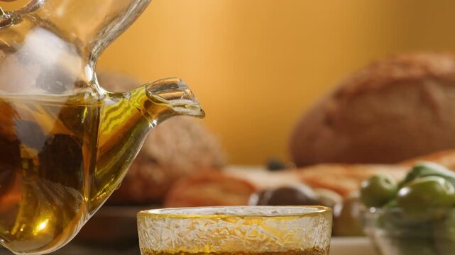 Olive oil extra virgin, Chef pouring fresh olive oil over Mediterranean table with olives and bread
