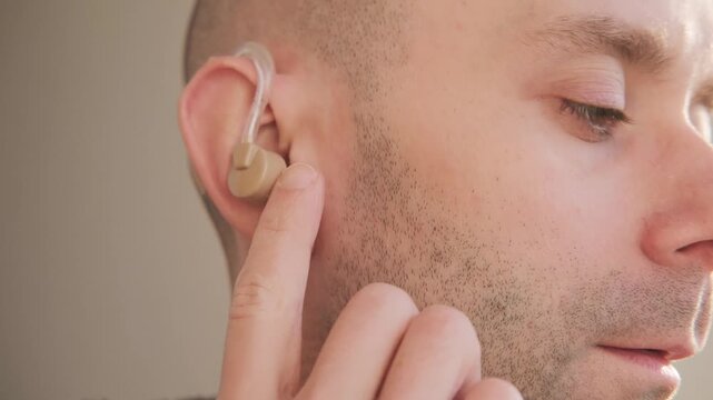 Closeup man wearing beige behind-the-ear hearing aid, modern medical device hearing loss compensation, audiology support, ear health and deafness, Medical tech solution improve auditory perception