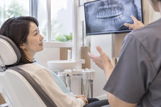 Dentist explaining a dental X-ray on a monitor to a patient during a daytime appointment