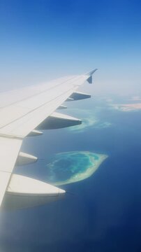 Airplane wing view above turquoise islands and ocean