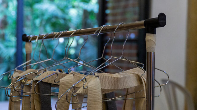 Close-up view of empty wire hangers and canvas tote bags on a metal clothing rack indoors