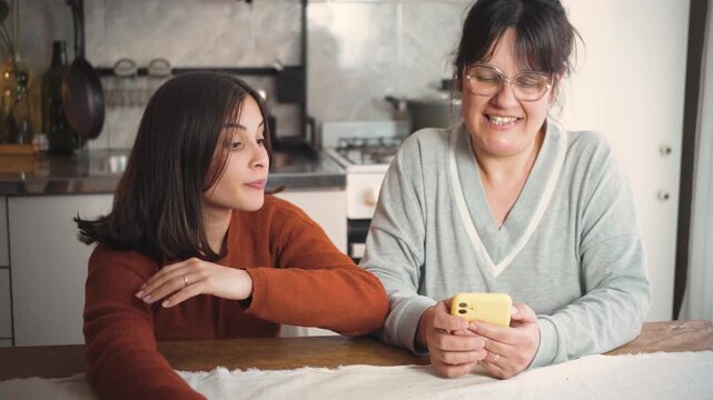 Young Latina woman at home feels ignored by her mother, who is constantly using her cellphone, highlighting family disconnection and excessive screen time.
