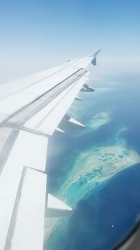 Scenic aerial view from airplane window over pristine island and turquoise waters