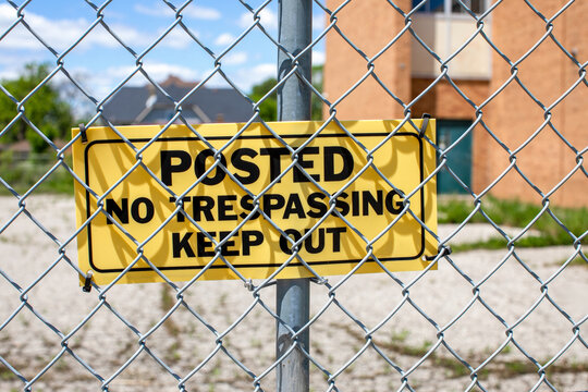No Trespassing Sign on Chain-Link Fence, School Zone