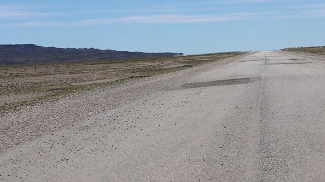 A dynamic perspective clip taken from a car traveling on a deteriorated asphalt highway in Argentine Patagonia, forcing the driver to swerve and weave.